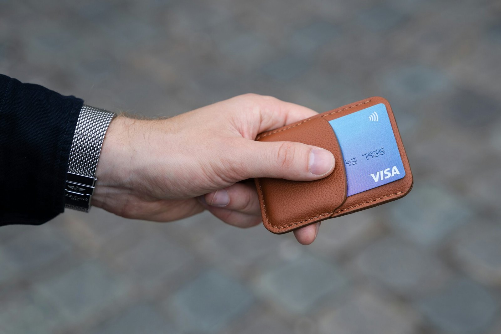 Photo of a brown card holder in a male hand.