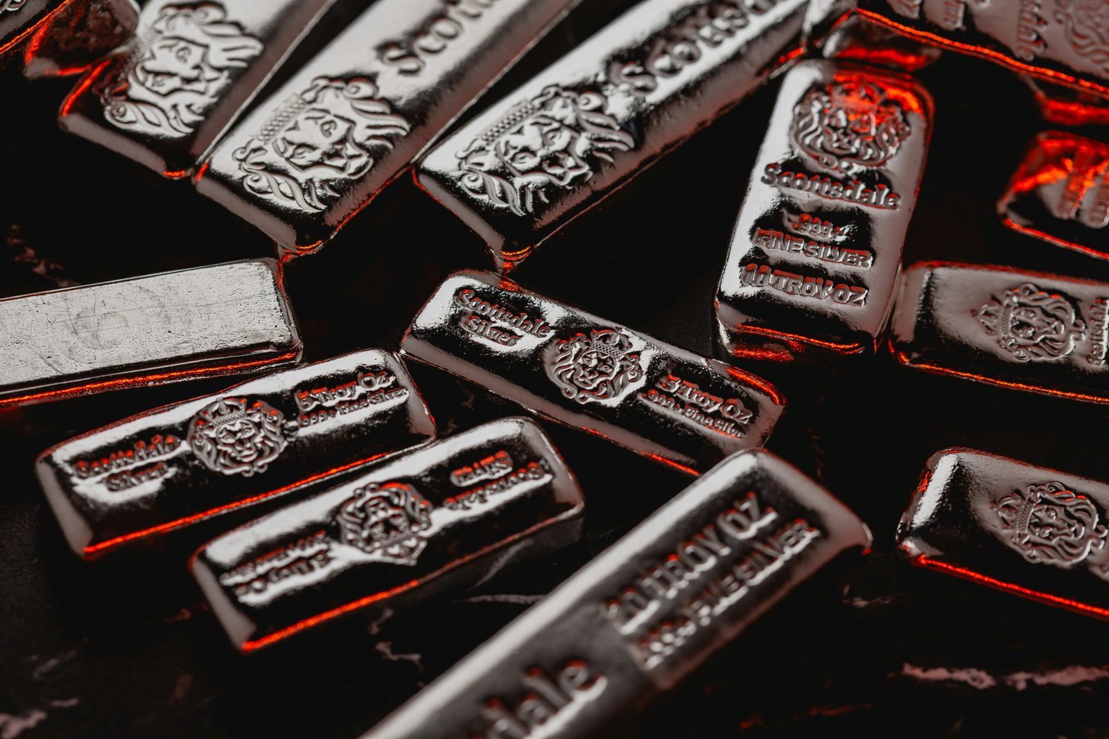 Scottsdale Mint cast silver bars stacked in a pile with cool red side light.