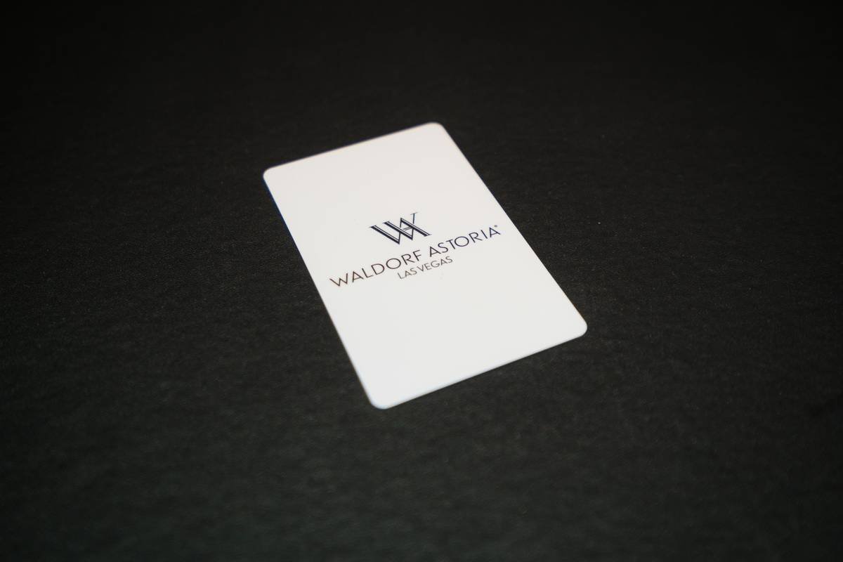 A close-up shot of a shiny black titanium credit card lying on a marble surface.